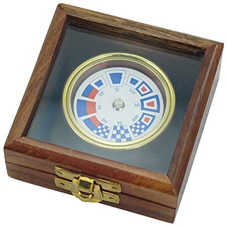 Brújula con banderas de latón en una caja decorativa de madera. 