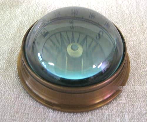 Brújula bajo cúpula arqueada de vidrio y latón antiguo. 